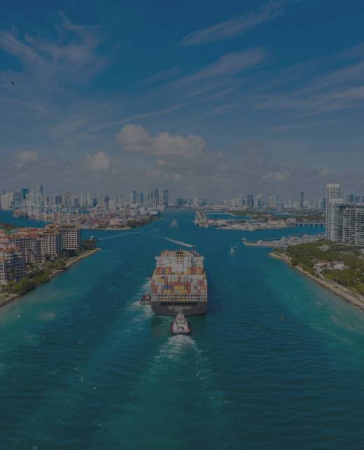 Large Container Ship Entering Harbor and Miami City on Sunny Day, USA. Aerial View.